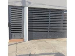 Portón gris a rayas con puerta de servicio